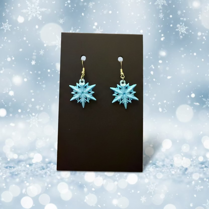 Blue snowflake earrings on a black card with a wooden surface background