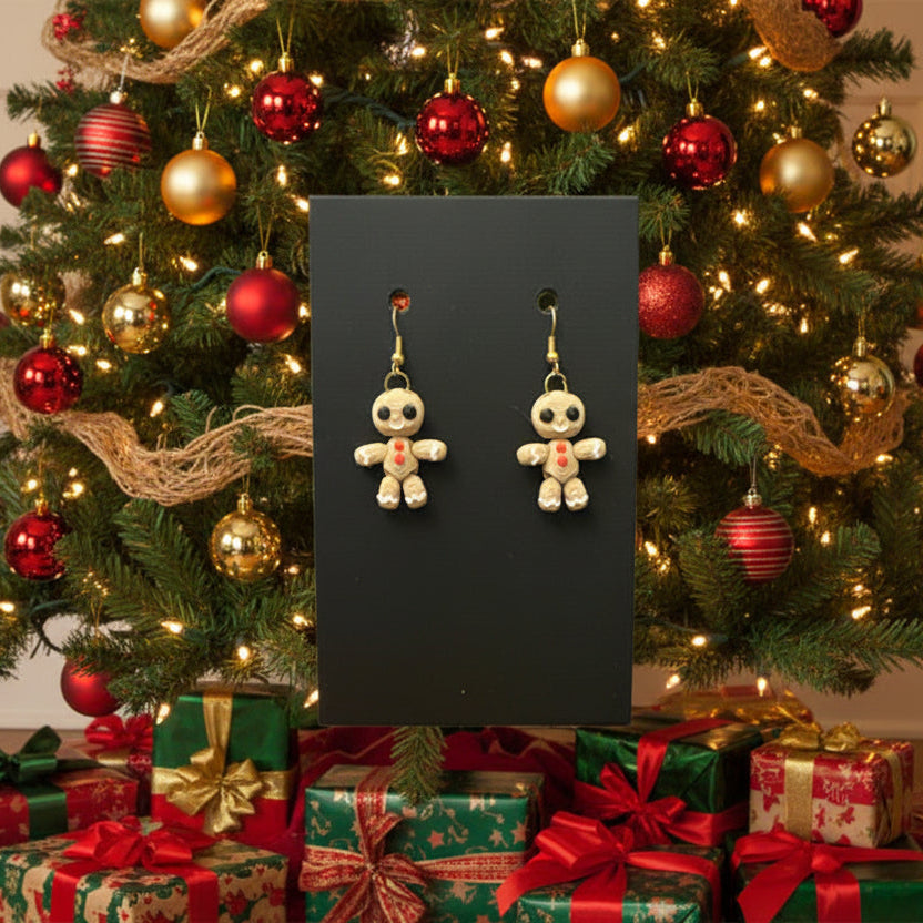Gingerbread man earrings displayed in front of a decorated Christmas tree and presents.